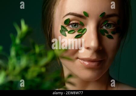 Nahaufnahme`s Gesicht einer jungen Frau mit Buchsbaumblättern. Spa und Wellness Konzept Vorlage Banner für Design. Werbung für kosmetische Produkte Stockfoto